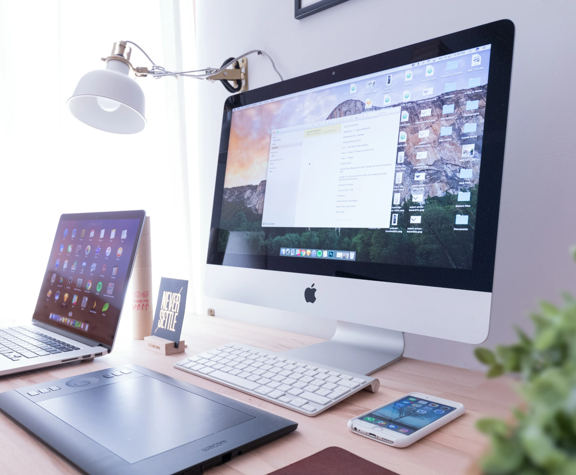 Desk containng a computer, phone, and tablet